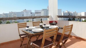 A dining table set on a balcony with white buildings in the background. - Cozy apartment in Torre Pacheco with WiFi (Torre Pacheco)