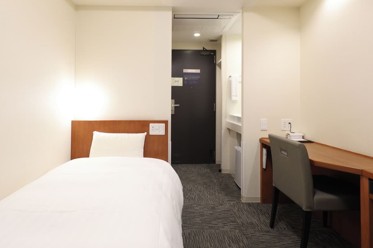 A hotel room with a bed, a desk, and a chair.