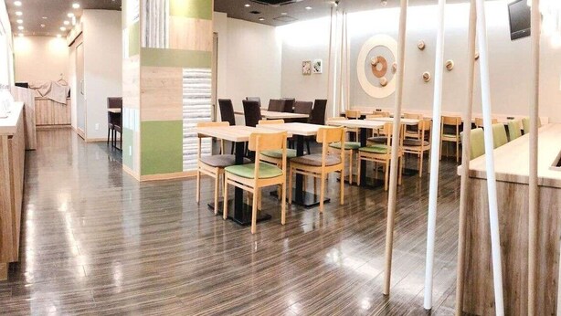 Ein Restaurant mit Holztischen und -stühlen, einem glatten Boden und einem modernen Innendesign.