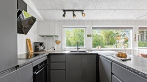 Una cocina moderna con una isla central, horno integrado y un amplio ventanal con vistas al exterior.