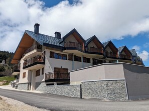 En byggnad med flera våningar, balkonger, en fasad av sten och en klar himmel.