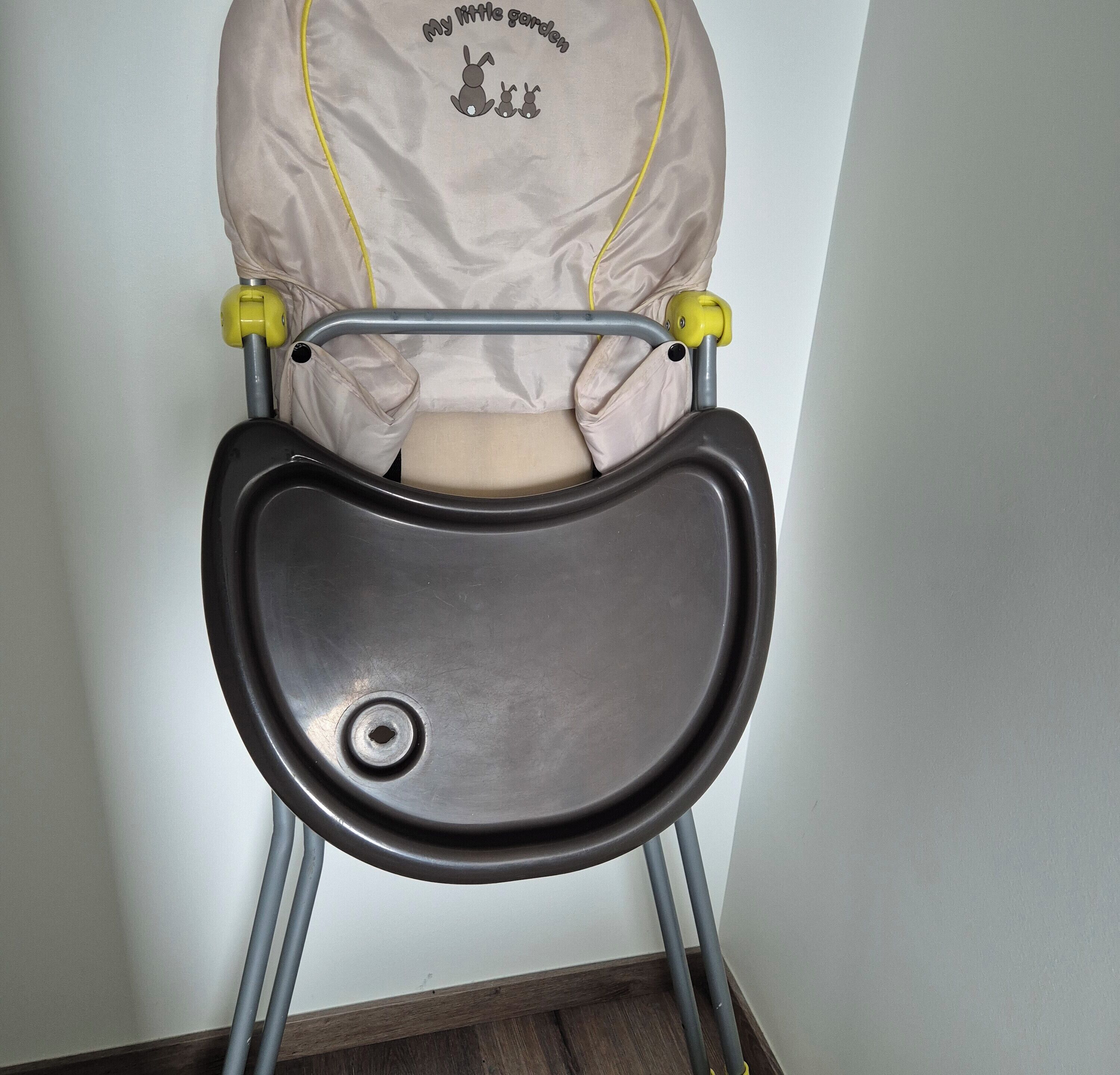 A baby stroller with a front tray and a cushion with a bunny design.
