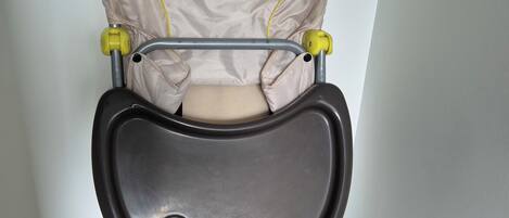 A baby stroller with a front tray and a cushion with a bunny design.