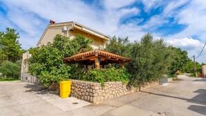 A house with a tiled roof, surrounded by greenery and a stone wall. - 1 bedroom beautiful apartment in Krusevo (Krusevo)