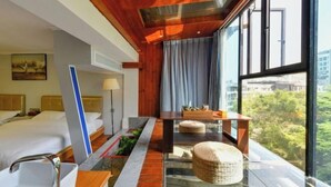 A modern hotel room with a large window, a bed, a desk, and a small indoor garden. - Xiamen Yuqiao Villa (International Convention and Exhibition Center Huandao Road Branch) (Xiamen)