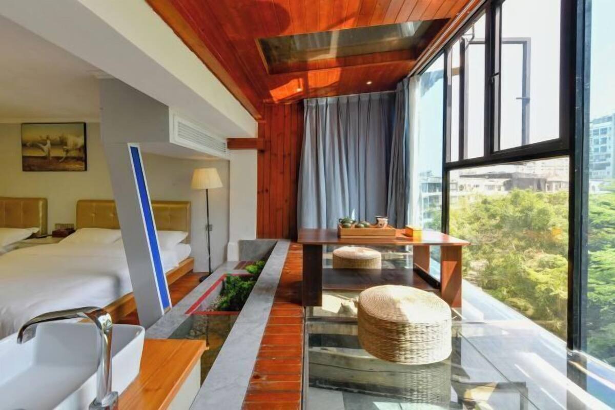 Une chambre d’hôtel moderne dotée d’une grande fenêtre, d’un lit, d’un bureau et d’un petit jardin intérieur.