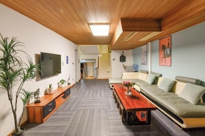 A modern living room with a sofa, a coffee table, a TV, and a staircase in the background. - Xiamen Yuqiao Villa (International Convention and Exhibition Center Huandao Road Branch) (Xiamen)