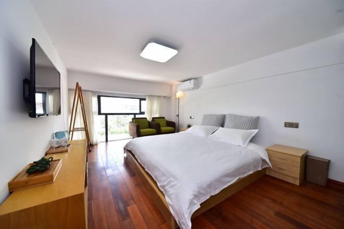 Une chambre moderne avec un grand lit, un bureau, une chaise et un téléviseur.