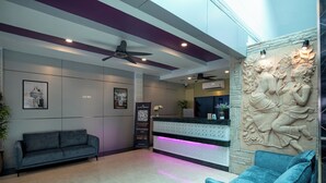 Un área de recepción moderna con un sofá, una mesa de recepción y un elemento decorativo en la pared.