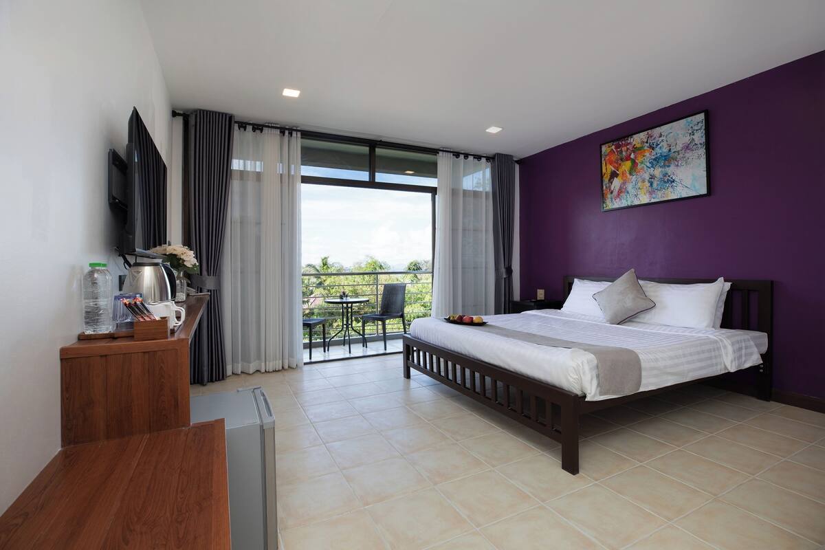 Una habitación de hotel moderna con cama, escritorio, televisión y balcón con vistas.