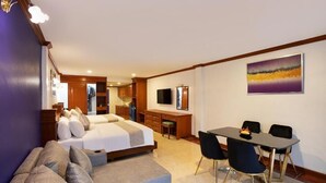 Una habitación de hotel con cama, escritorio, televisor y una zona de comedor con sillas.