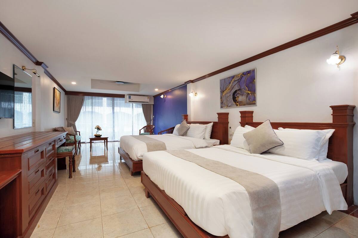 Una habitación de hotel con dos camas, un aparador de madera, un escritorio y una silla.