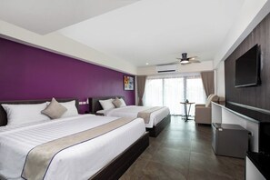 Une chambre d’hôtel avec deux lits, une télévision, un ventilateur de plafond et une fenêtre avec des rideaux.
