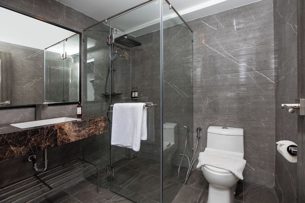 A modern bathroom with a glass-enclosed shower, a white toilet, and a marble vanity.