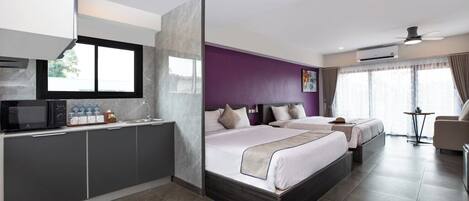 Una habitación de hotel moderna con una cama grande, un sofá independiente, una kitchenette y vistas al exterior.