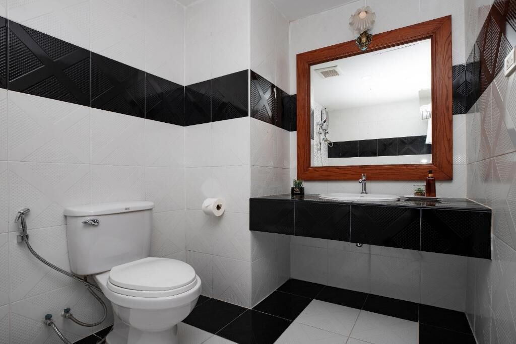 A bathroom with a toilet, sink, and mirror.