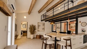 A modern kitchen with a central island, bar stools, and a dining area. - Le 522 – Nature Retreat & Jacuzzi (Ventabren)
