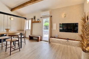 Un intérieur moderne avec une table à manger en bois, des chaises, un banc, un téléviseur fixé au mur et un appareil de climatisation.