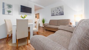 A modern living room with a sofa, chairs, a dining table, and a TV. - 2 bedroom lovely apartment in Povljana (Povljana)