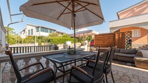 An outdoor patio with a table and chairs, a large umbrella, and a wicker sofa. - 2 bedroom lovely apartment in Povljana (Povljana)