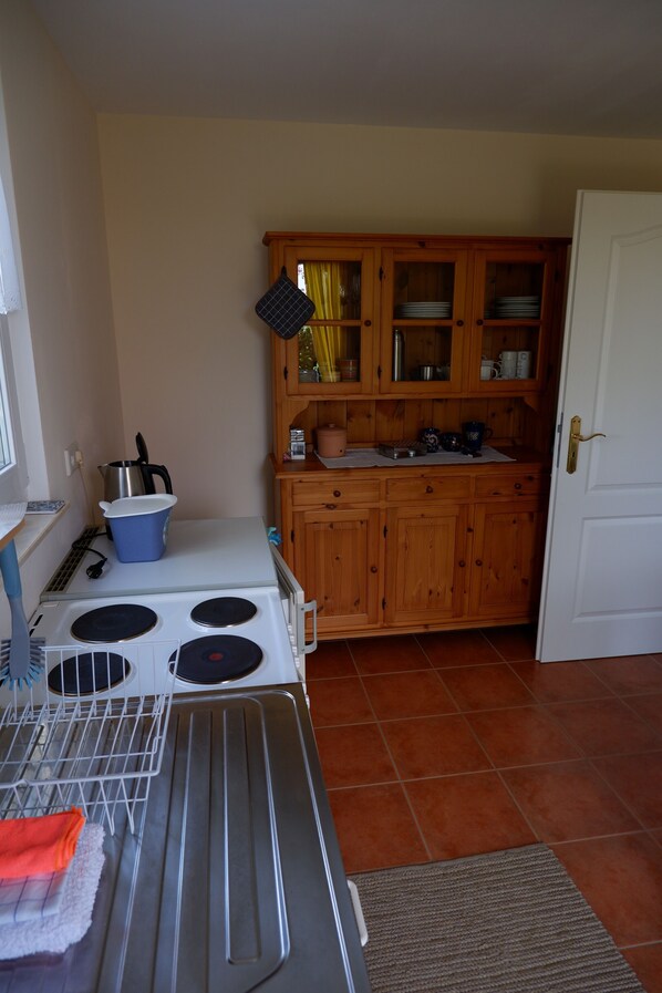 A kitchen with wooden cabinets, a stove, and a drying rack.