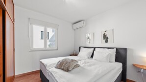 A bedroom with a bed, a nightstand, a window, and an air conditioning unit. - Awesome apartment in Rogoznica with WiFi (Rogoznica)