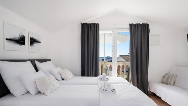 A hotel room with two beds, a balcony with a view of buildings, and a white color scheme. - Awesome apartment in Rogoznica with WiFi (Rogoznica)