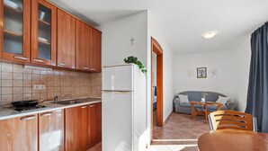 A compact kitchen with wooden cabinets, a white refrigerator, and a dining area with a table and chairs. - Awesome apartment in Rogoznica with WiFi (Rogoznica)