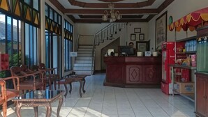 Una hall d'albergo con reception, una scala e un'area salotto con mobili in legno.