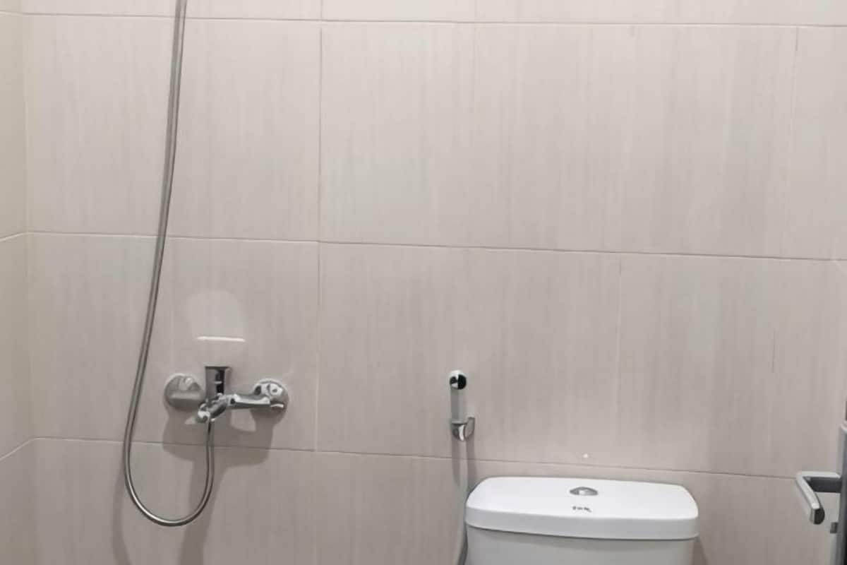 A bathroom with a toilet, a shower, and a wall-mounted faucet.