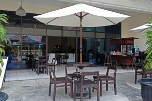 An outdoor seating area with tables and chairs, umbrellas, and a vending machine. - Borobudur Hotel Jogja (Mlati)