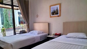 Una camera d'albergo con due letti, un comodino con il telefono e una finestra con tende.