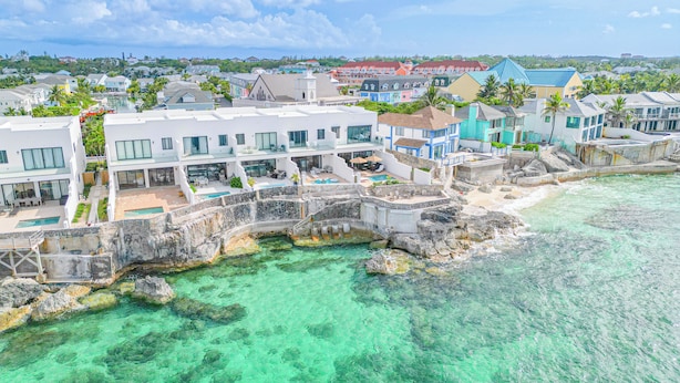 A coastal hotel with multiple buildings, a swimming pool, and clear turquoise waters. - 3 BR Oceanfront Beach House with Private Pool Gated Community Staircase to Ocean (Nassau)