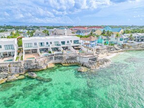 A coastal resort with multiple buildings, a swimming pool, and clear turquoise waters.
