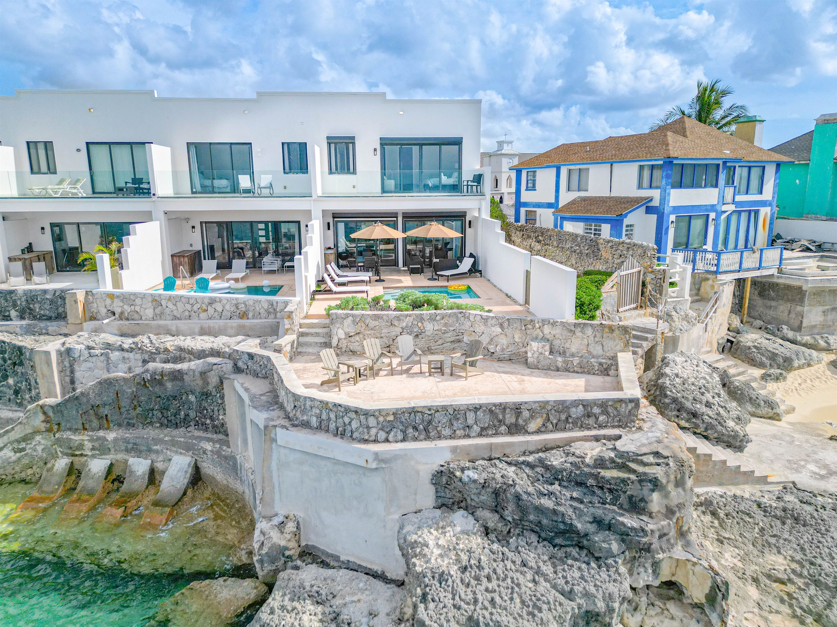 A modern resort with a pool, outdoor seating, and a stone retaining wall.