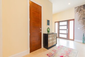 A hallway with a wooden door, a cabinet with a decorative front, and a patterned rug on the floor. - Oceanfront with Beach Access & Private Pool 3BR (Nassau)