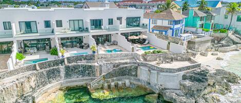 A resort with a pool, outdoor seating, and a view of the ocean.