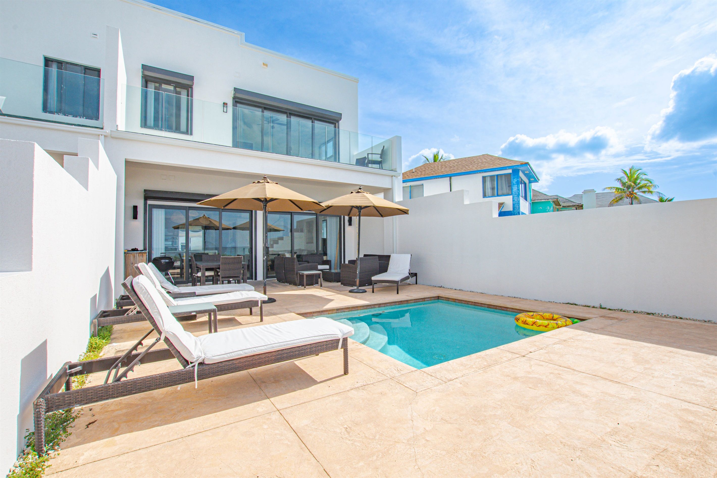 Une maison moderne dotée d’une piscine, d’un espace salon extérieur et offrant une vue sur la mer.