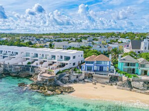 A coastal residential area with modern houses, a beach, and clear turquoise waters. - Oceanfront with Beach Access & Private Pool 3BR (Nassau)