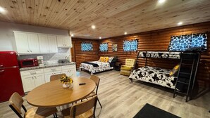 Ein gemütliches, modernes Blockhaus mit Küche, Essbereich und einem Schlafbereich mit Etagenbett.
