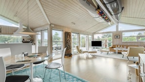 En rummelig, lys stue med højt til loftet, spiseplads og opholdsområde med tv.