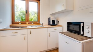 A compact kitchen with a coffee machine, a microwave, and a sink.