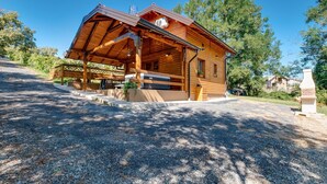A wooden cabin with a covered porch, a grill, and a stone fireplace.