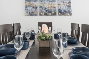 A dining table set with blue plates, wine glasses, and a centerpiece with flowers and a candle. - New! Modern 4BR walk to Reno-Sparks Conv Center, Atlantis Casino & shops (Reno)
