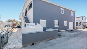 A modern two-story building with a grey facade, a small outdoor seating area, and a staircase leading to the entrance. - Nice apartment in Vir with WiFi (Vir)