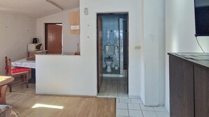 A room with a wooden dining table, a microwave, a small cabinet, and a television on a stand. - Nice apartment in Vir with WiFi (Vir)