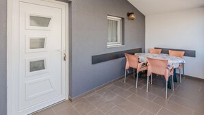 A dining area with a table and chairs, a white door with glass panels, and a small window with a curtain. - Nice apartment in Vir with WiFi (Vir)