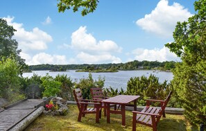 A wooden deck with a table and chairs overlooking a lake with boats and houses in the distance. - Nice home in Ronneby with WiFi (Ronneby)