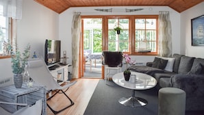 A cozy living room with a wooden ceiling, a sofa, a coffee table, and a TV. - Nice home in Ronneby with WiFi (Ronneby)
