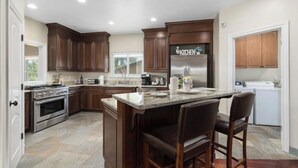 A modern kitchen with dark wooden cabinets, a stainless steel refrigerator, and a marble countertop.